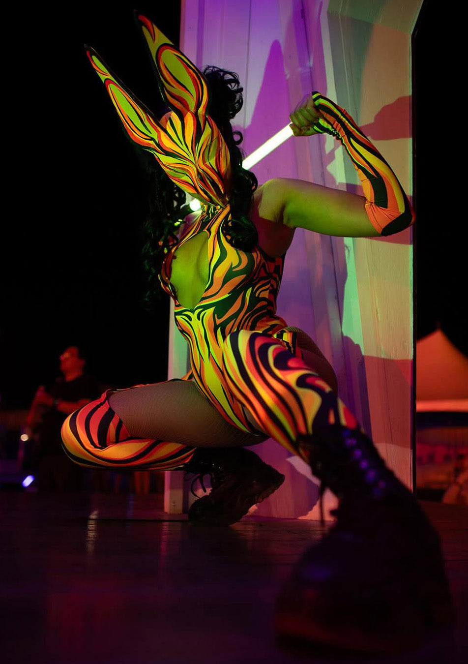 person during a rave stage performance wearing a neon mathing set