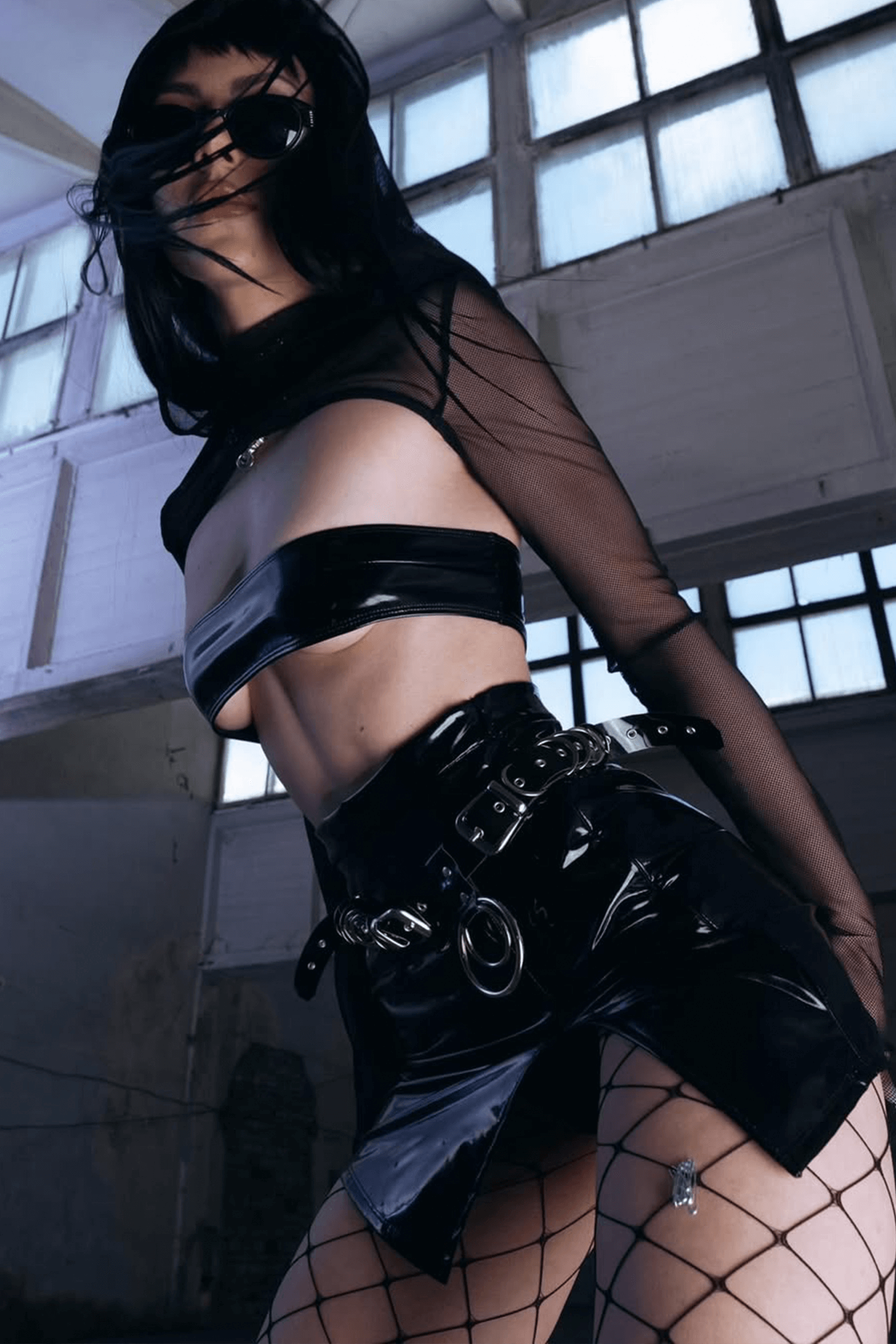 Woman in an all-black EDM set with micro tube top and see-through sleeves