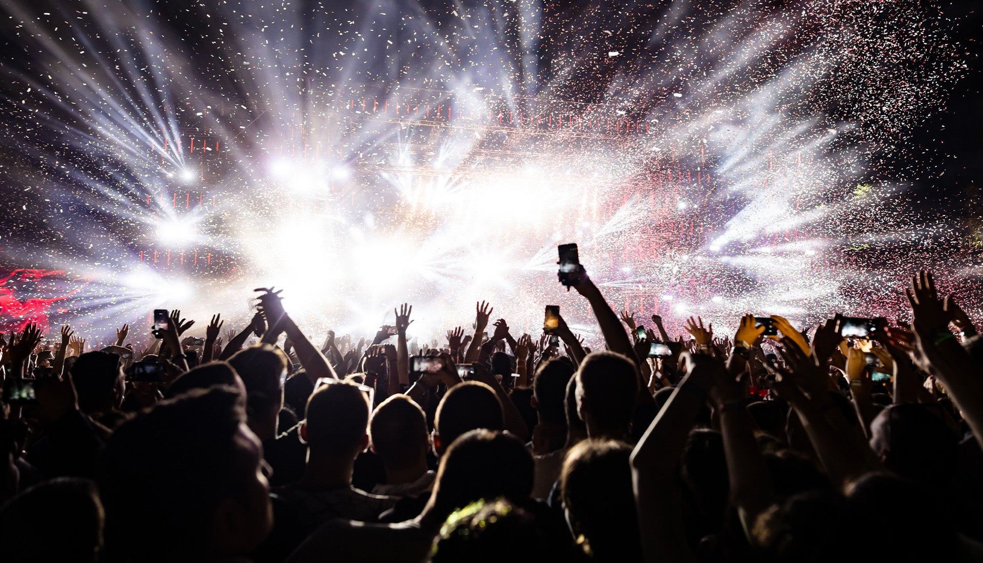 big crowd having fun under the lights of an EDM festival