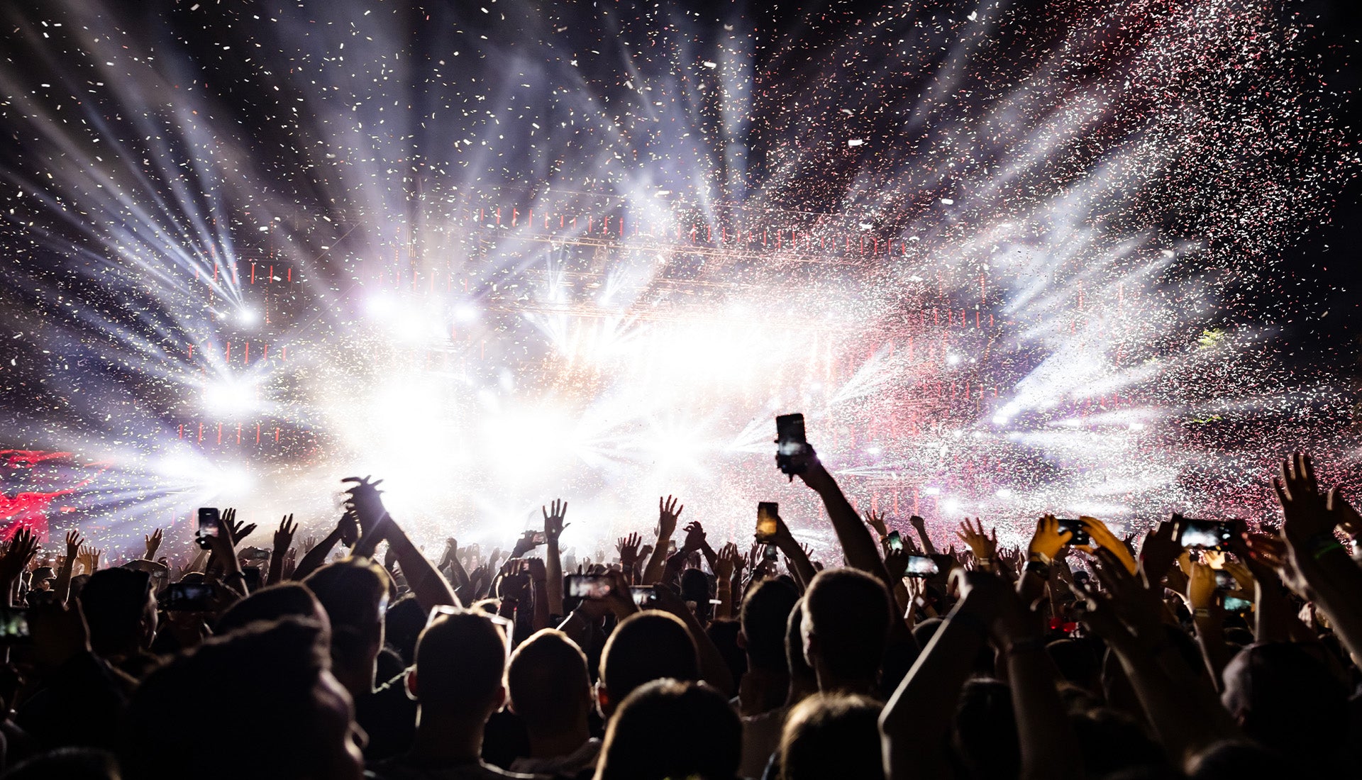 a giant crowd partying at a concert in front of a lit stage