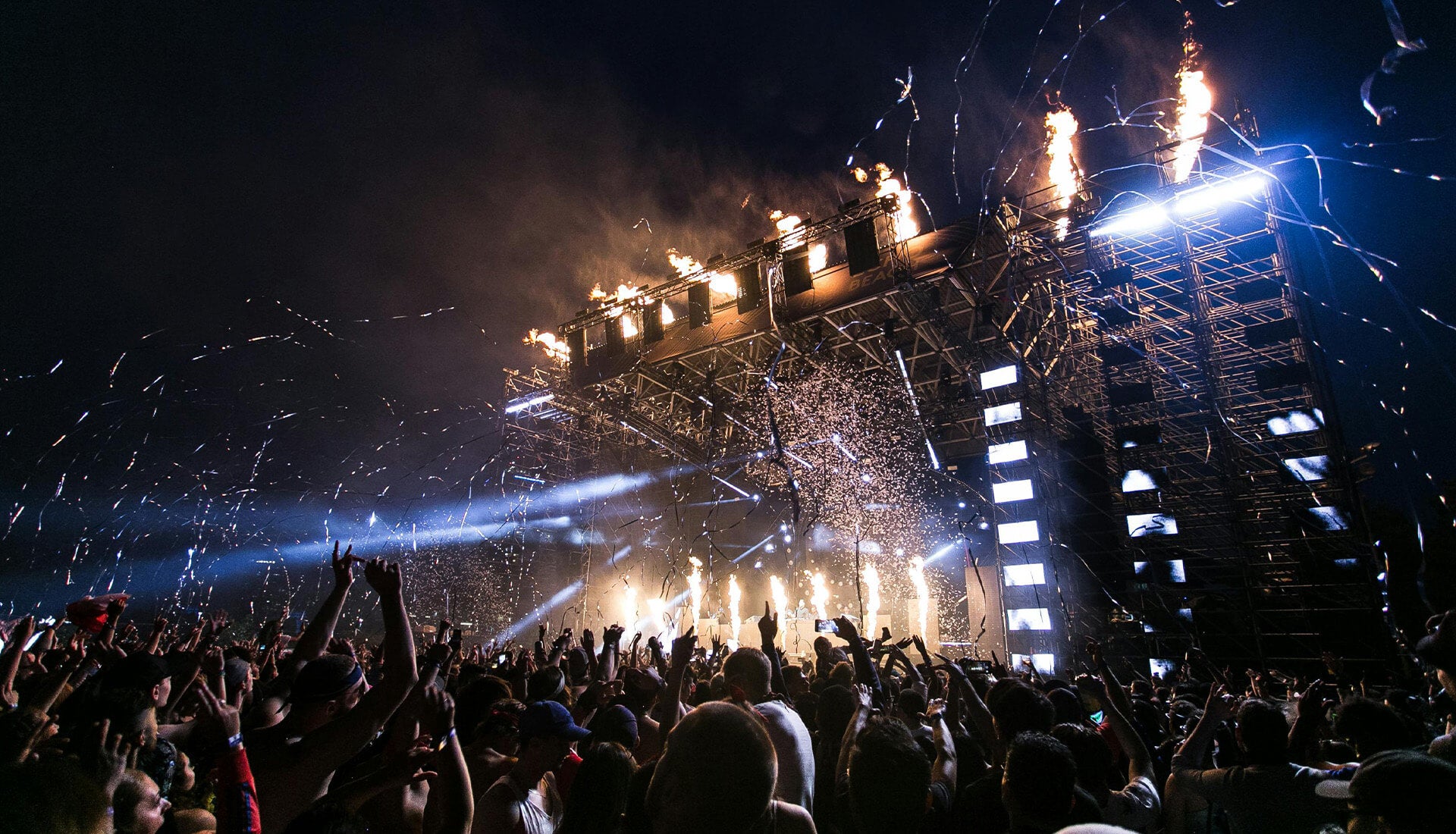 a night-time rave stage lit with fire and lightings