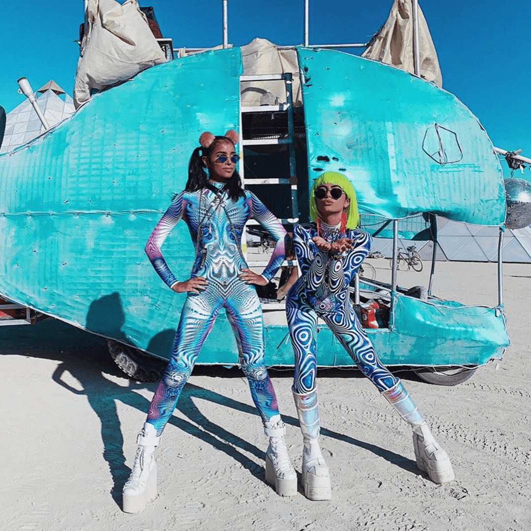 Two women in vibrant, patterned jumpsuits at Burning Man
